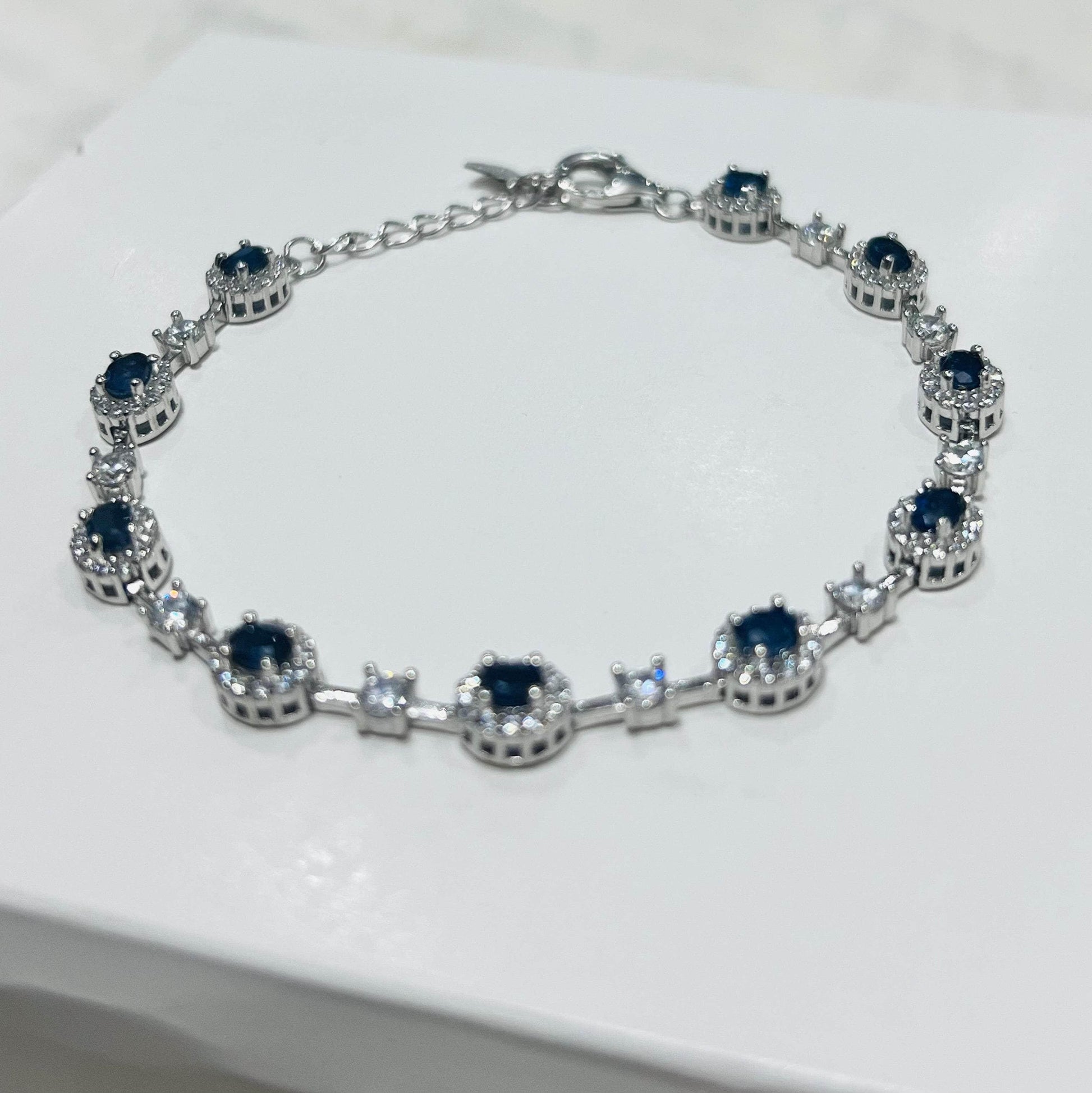 Angled perspective of a rhodium-plated sapphire bracelet, highlighting the brilliant blue gemstones and shimmering accents.