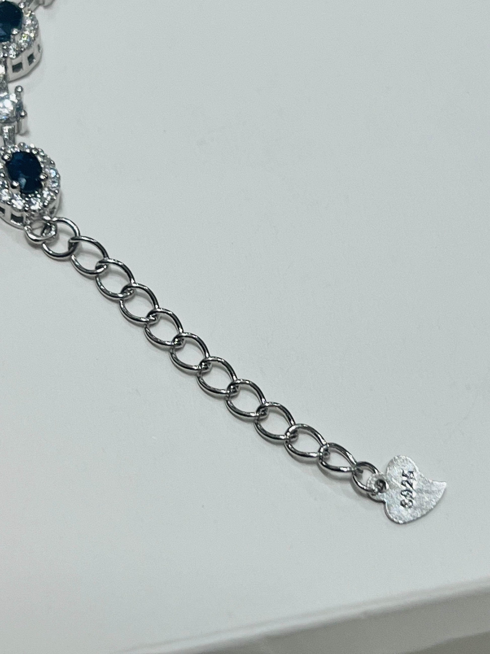 Detailed view of the adjustable chain and 'S925' marked heart clasp on a rhodium-plated sapphire bracelet.