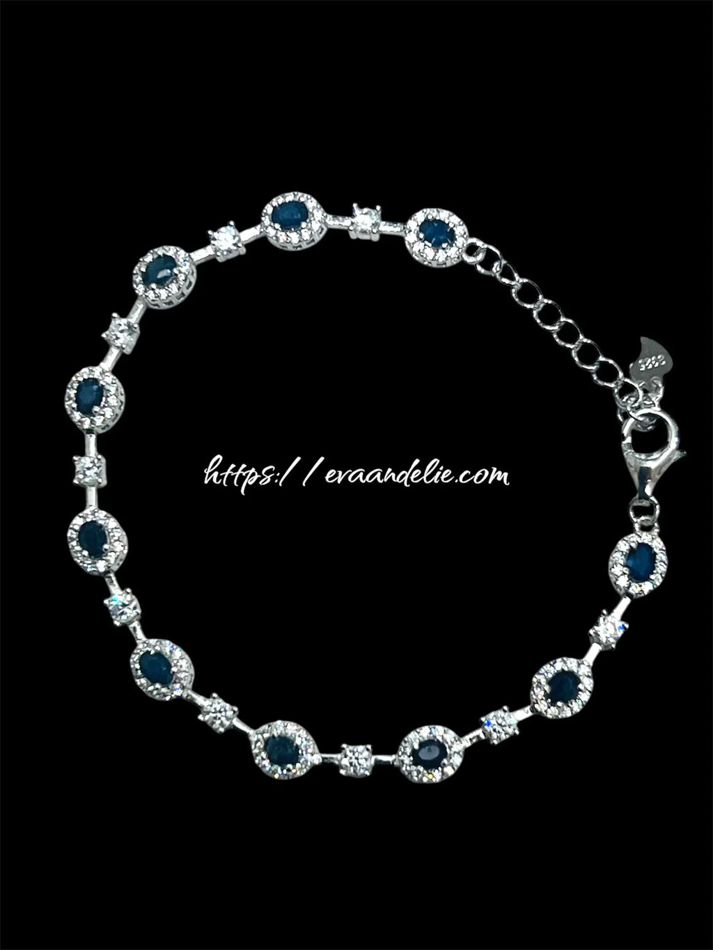 Elegant rhodium-plated bracelet with deep blue sapphires and clear sparkling accents, on a black background.