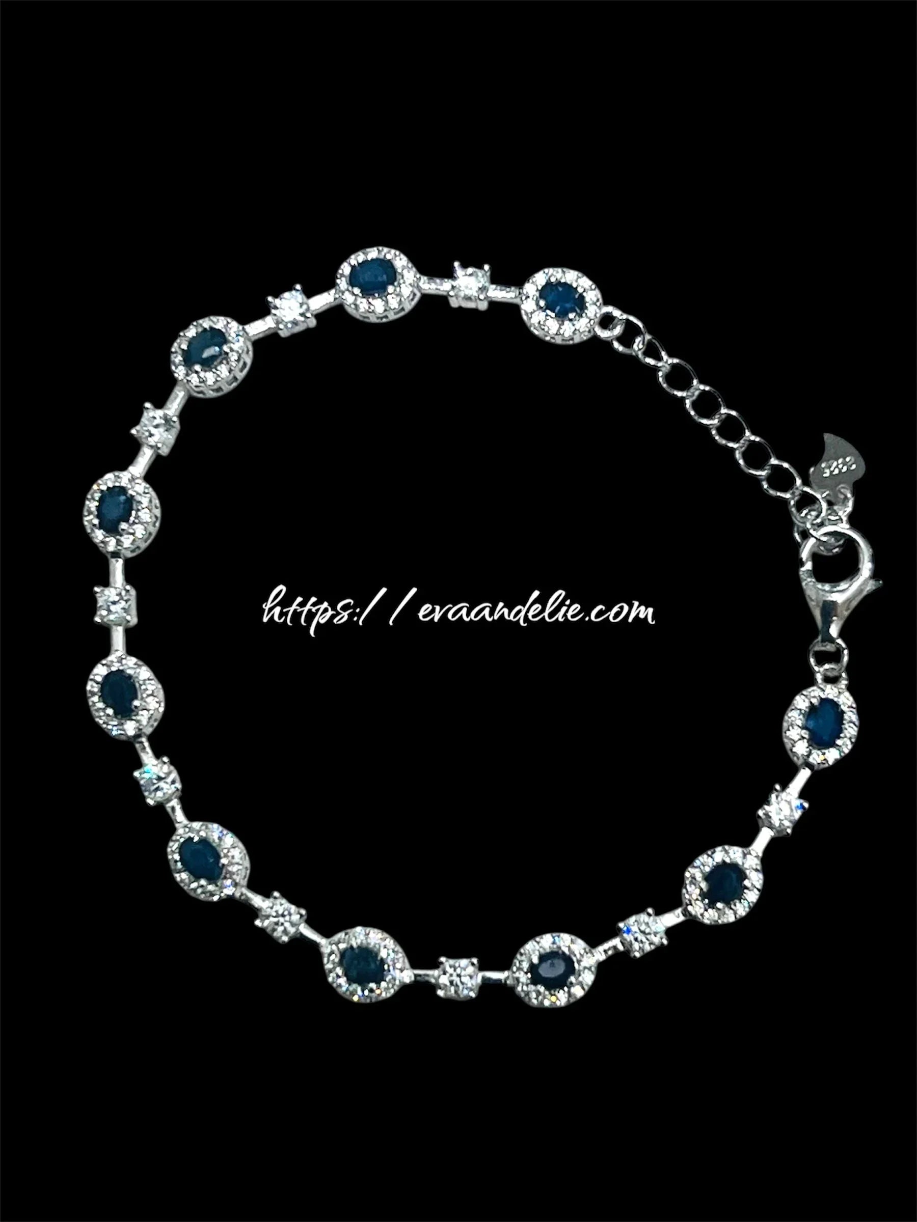 Elegant rhodium-plated bracelet with deep blue sapphires and clear sparkling accents, on a black background.