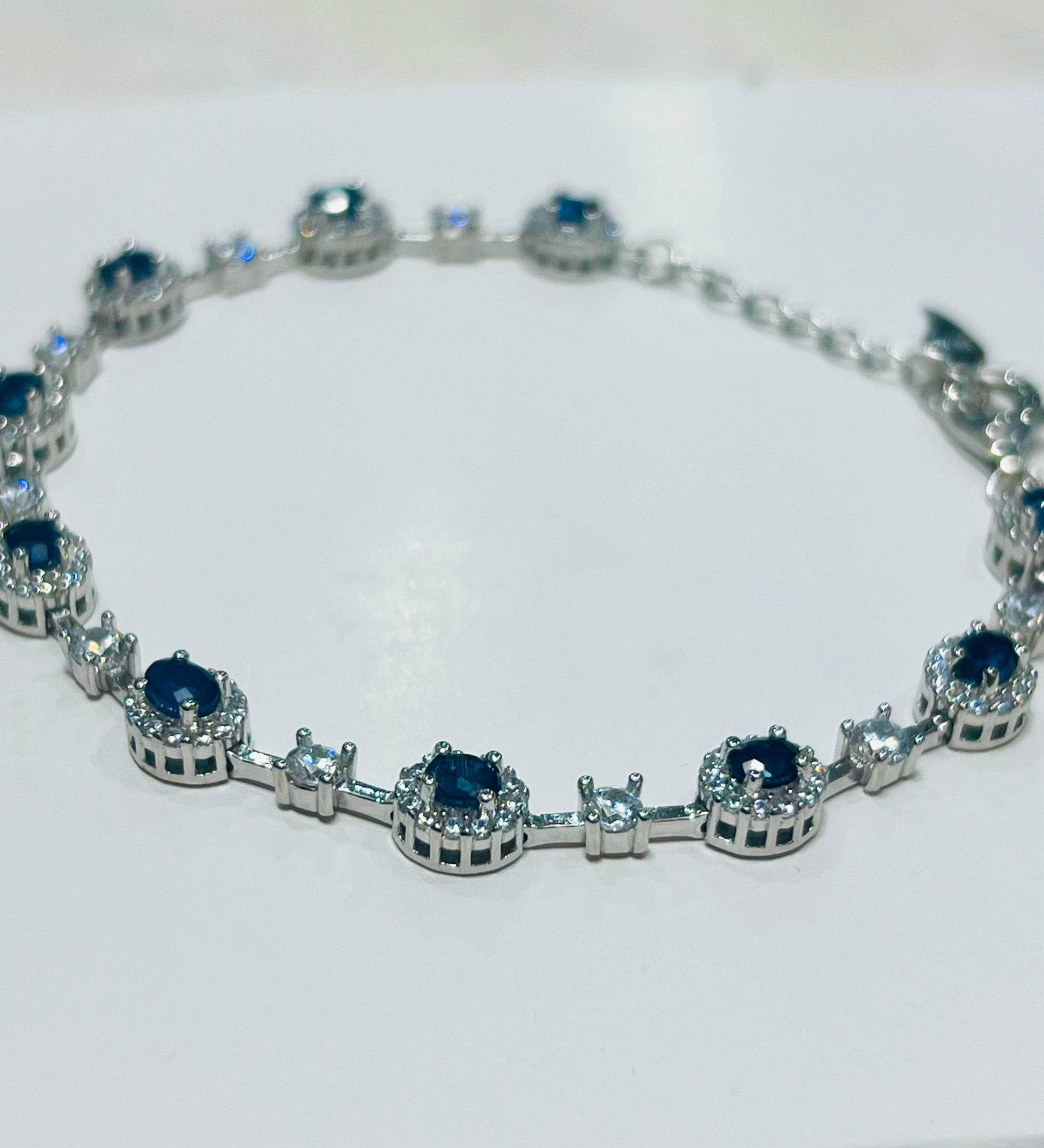 Close-up detail of a rhodium-plated sapphire bracelet, showcasing the intricate setting of the blue and white gemstones.