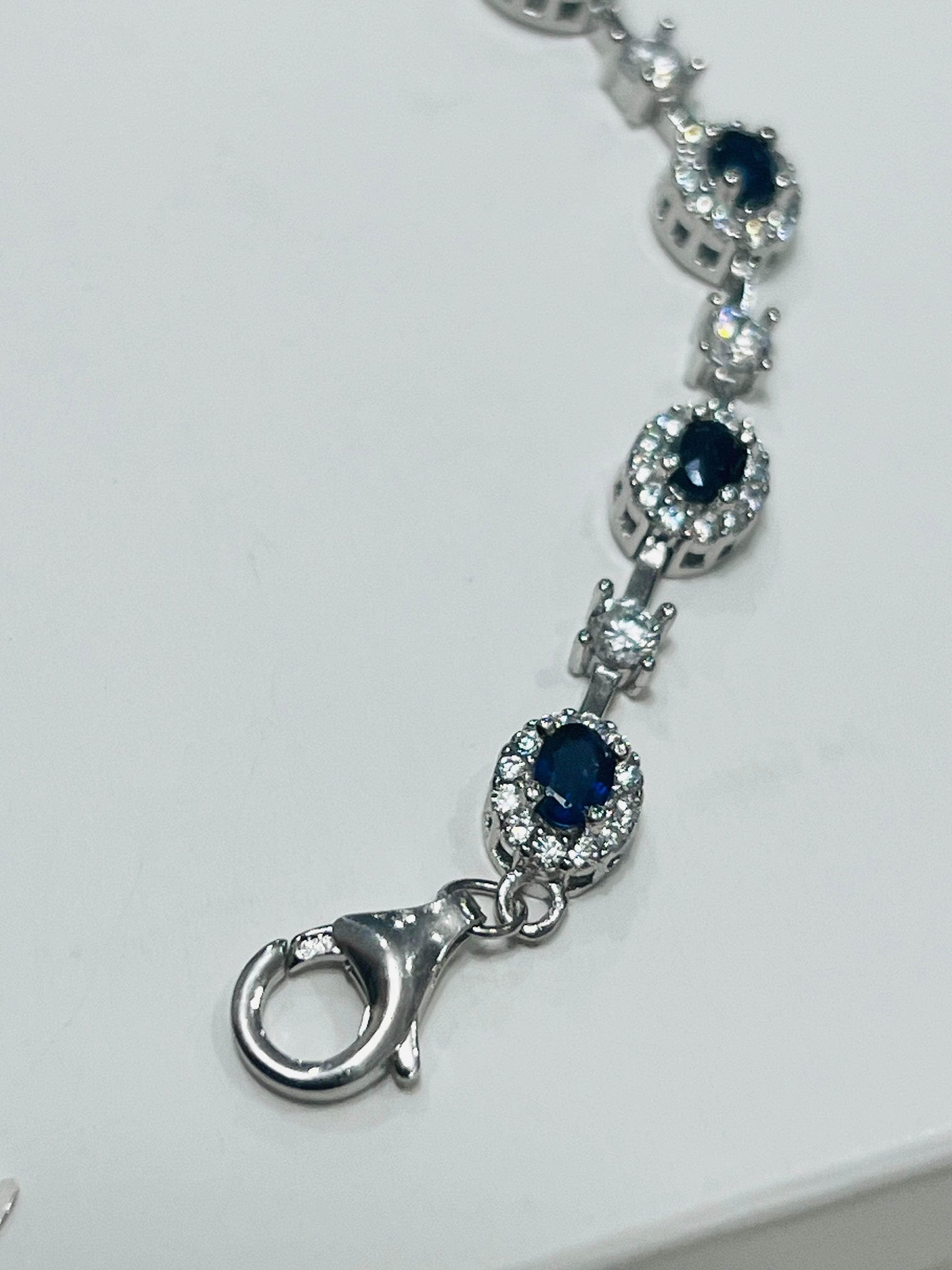 Close-up of the secure lobster claw clasp and a section of the rhodium-plated sapphire and accent stone bracelet.