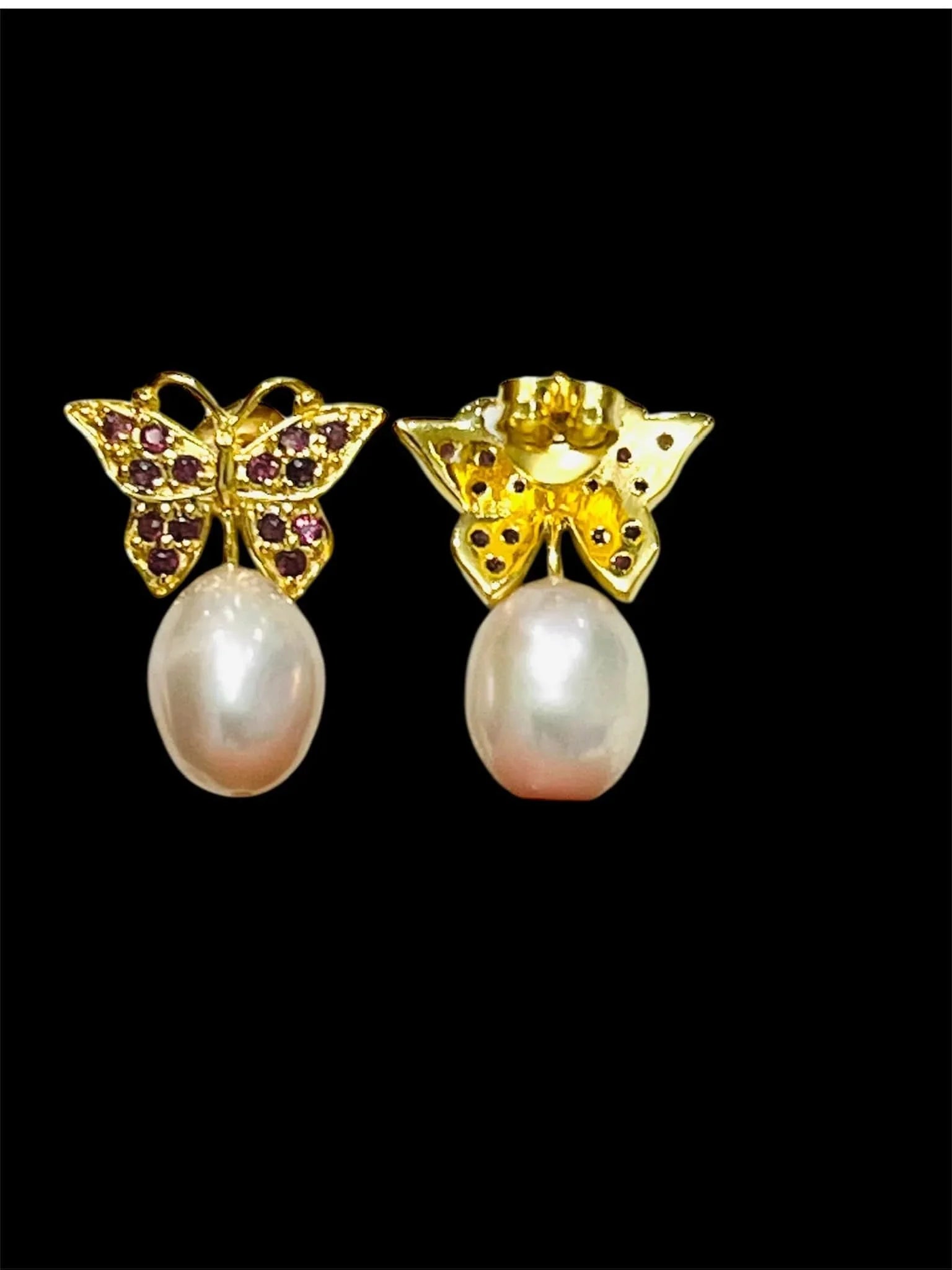 Rhodolite garnet butterfly earrings with pink pearl drops, contrasting black background.
