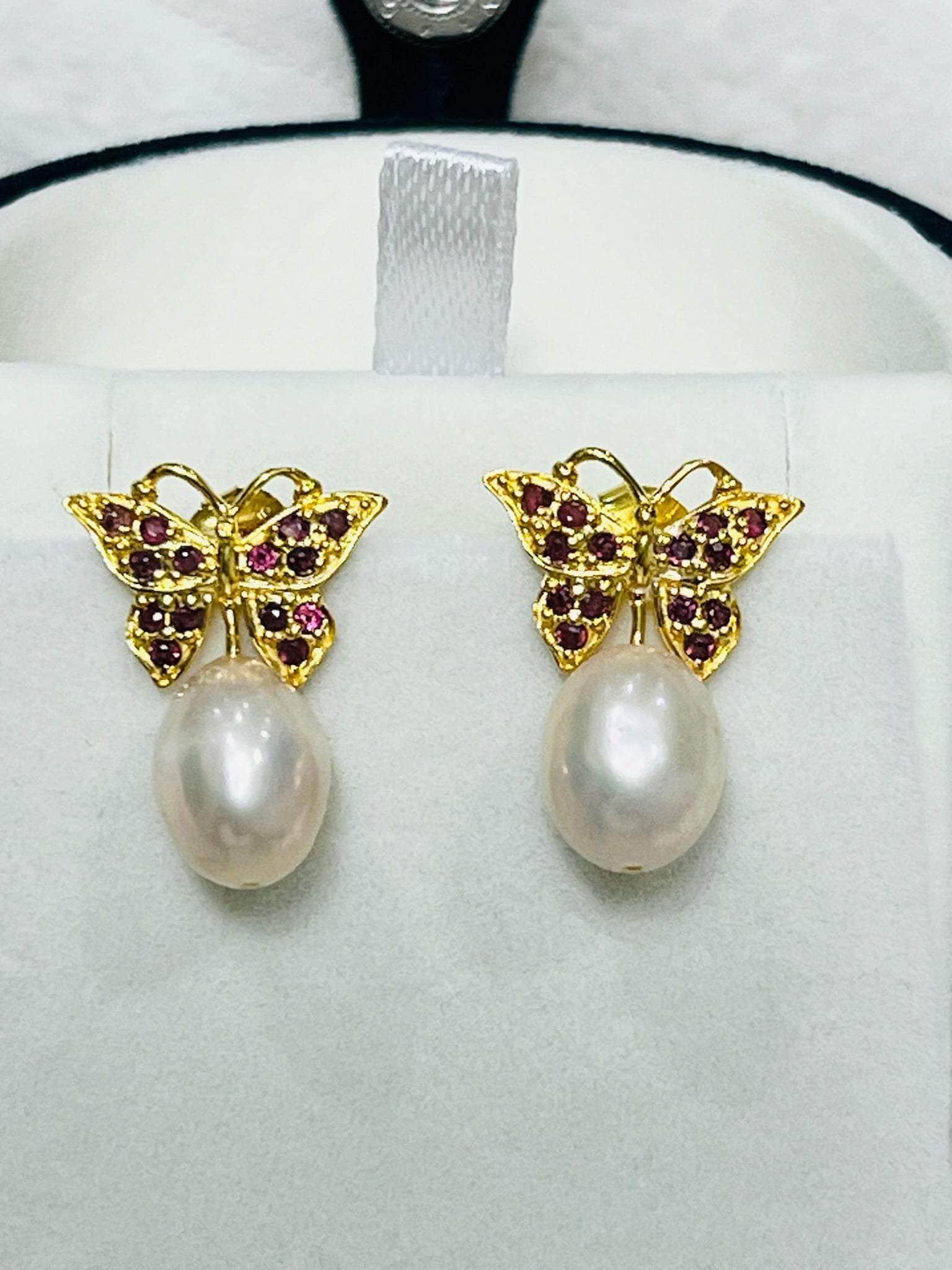 Exquisite rhodolite garnet butterfly earrings with gold settings and lustrous pink pearl drops, presented in a jewelry box.
