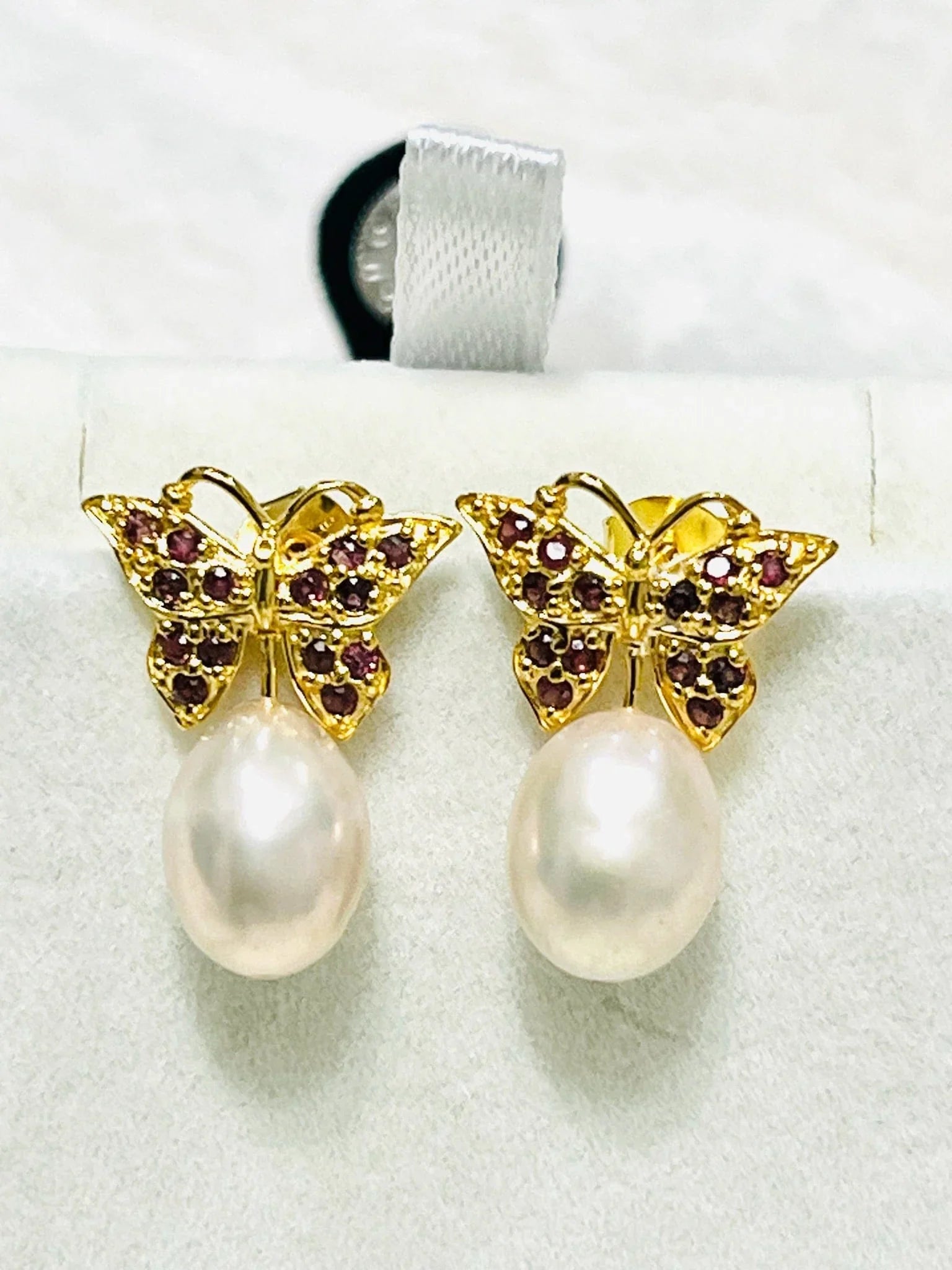 Front view of elegant rhodolite garnet butterfly earrings featuring vibrant red gemstones and lustrous pink pearls.