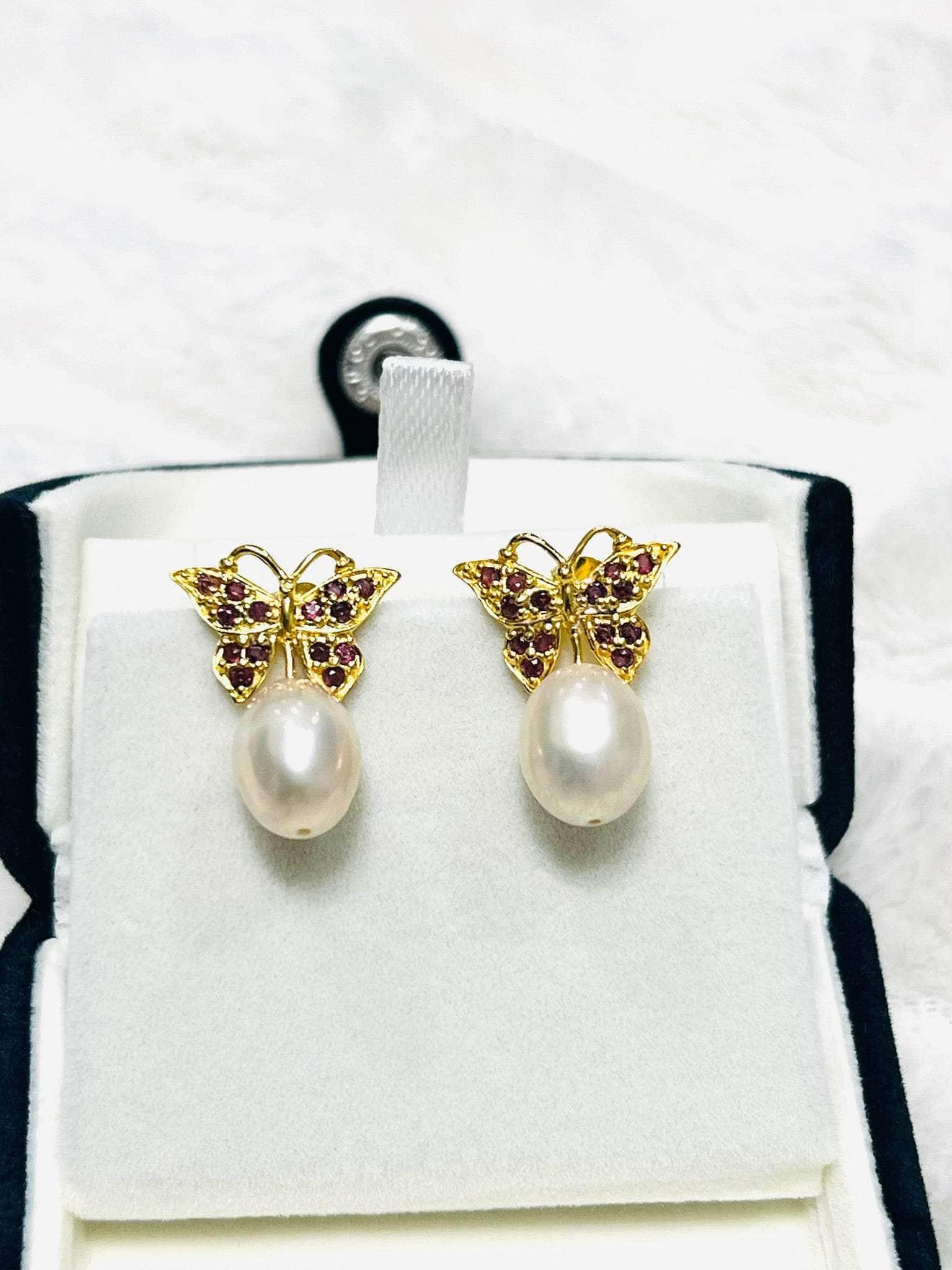 Elegant rhodolite garnet butterfly earrings with pink pearl drops, in a white jewelry box.