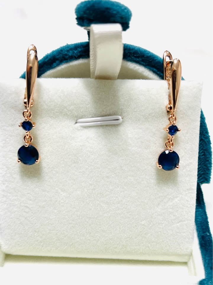 Close-up of exquisite rose gold dangle earrings with captivating blue sapphire gemstones, perfect for formal wear.