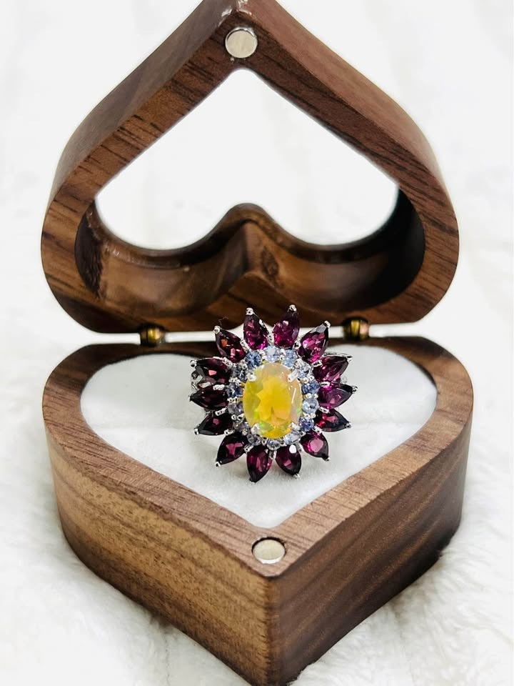 A stunning sterling silver ring with a fiery opal center, rubellite petals, and tanzanite accents.