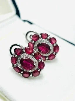 Angled close-up of the ruby and diamond halo earrings, capturing the sparkle of diamond accents around the central oval rubies