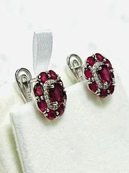 Angled profile shot of the ruby and diamond halo earrings, showing the brilliant red rubies and intricate silver setting