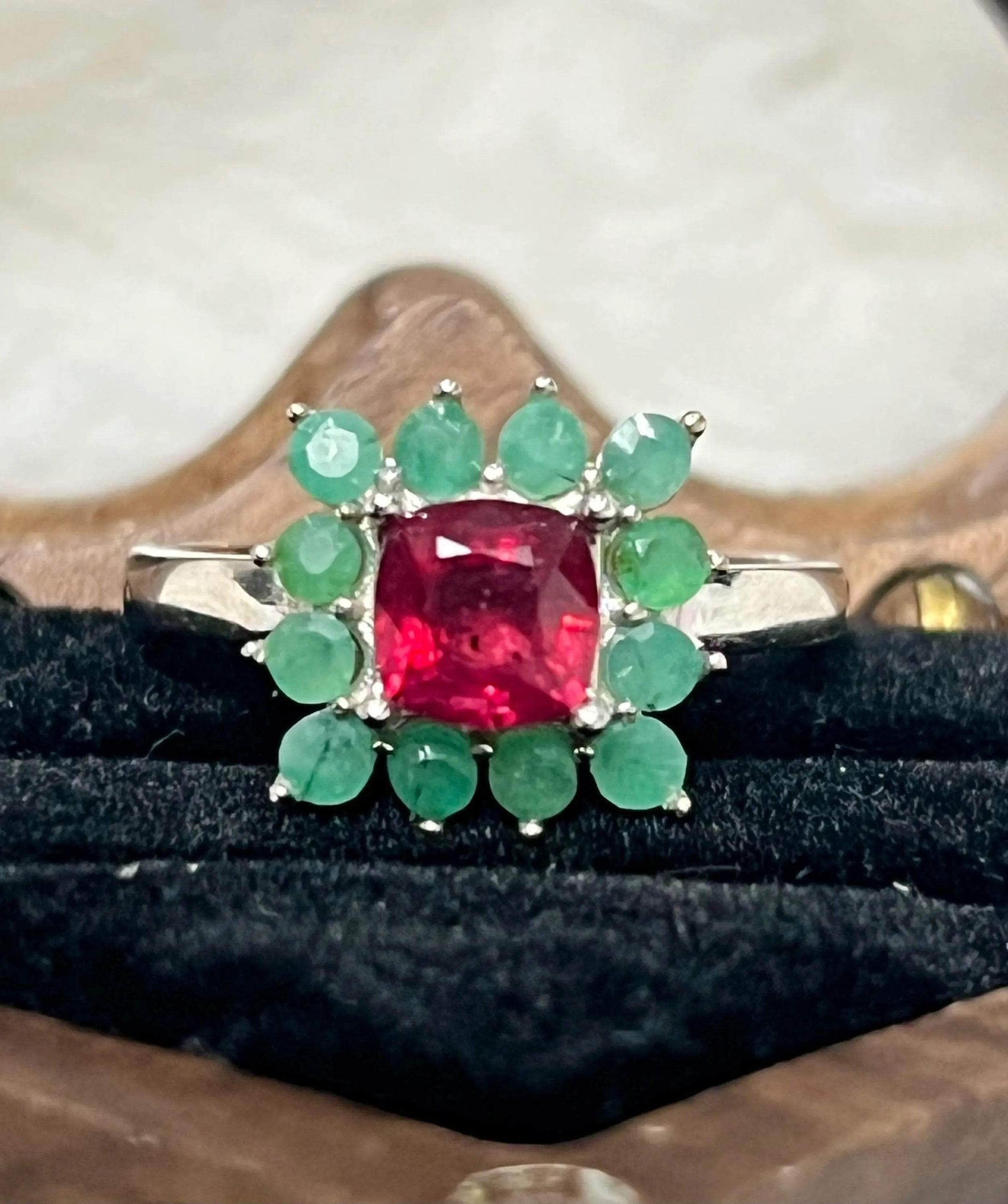 Close-up of a handmade sterling silver ring featuring a vibrant ruby center stone surrounded by emeralds.