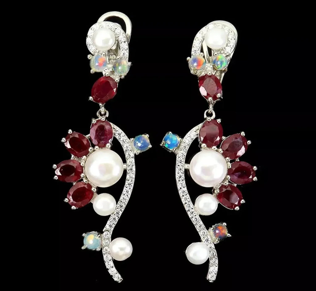 Stunning long earrings featuring rubies, opals, and pearls in a silver setting, displayed against black.