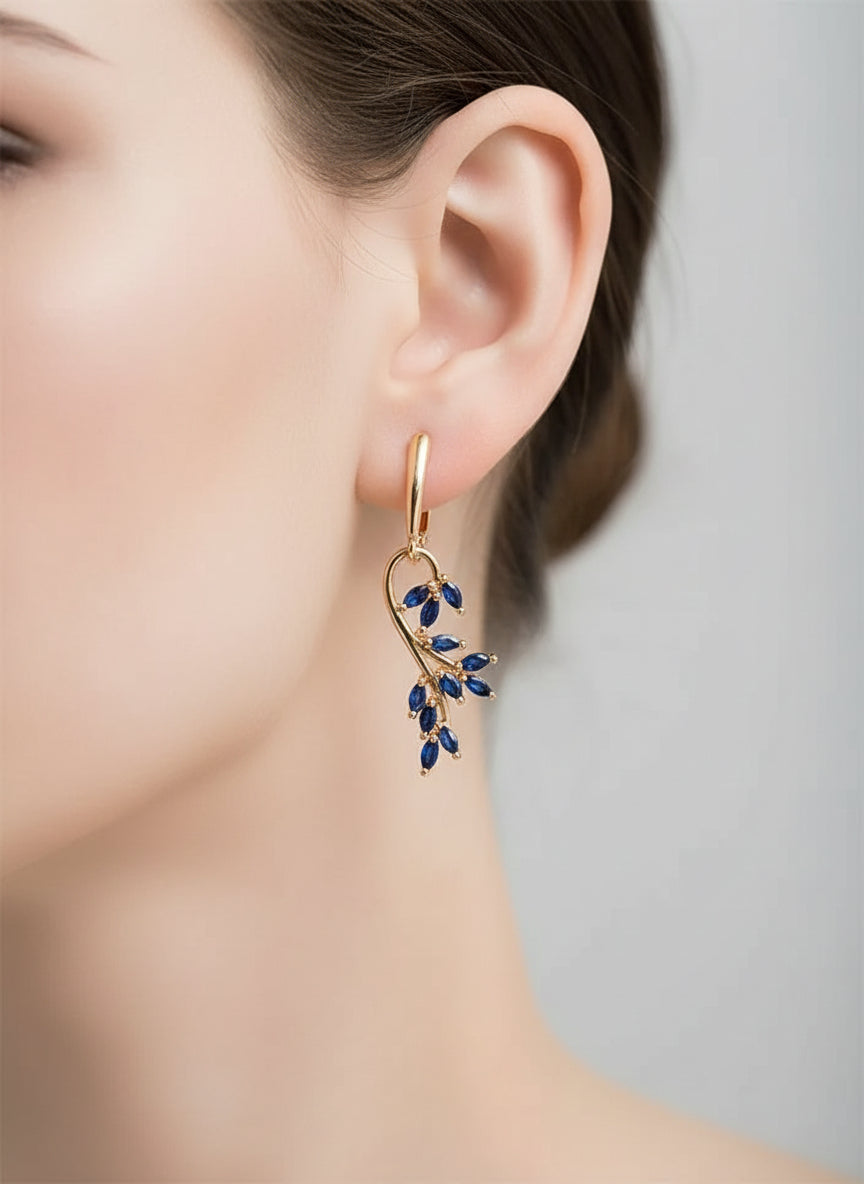 Single 14K rose gold dangle earring with sapphire gemstones, modeled on a mannequin head.