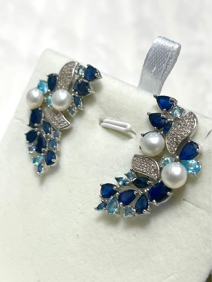 Stunning silver floral cluster earrings with a mix of blue sapphires, white topaz, and lustrous pearls.