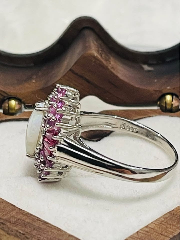 Side view of a silver ring with a marquise Australian opal and pink sapphire halo.
