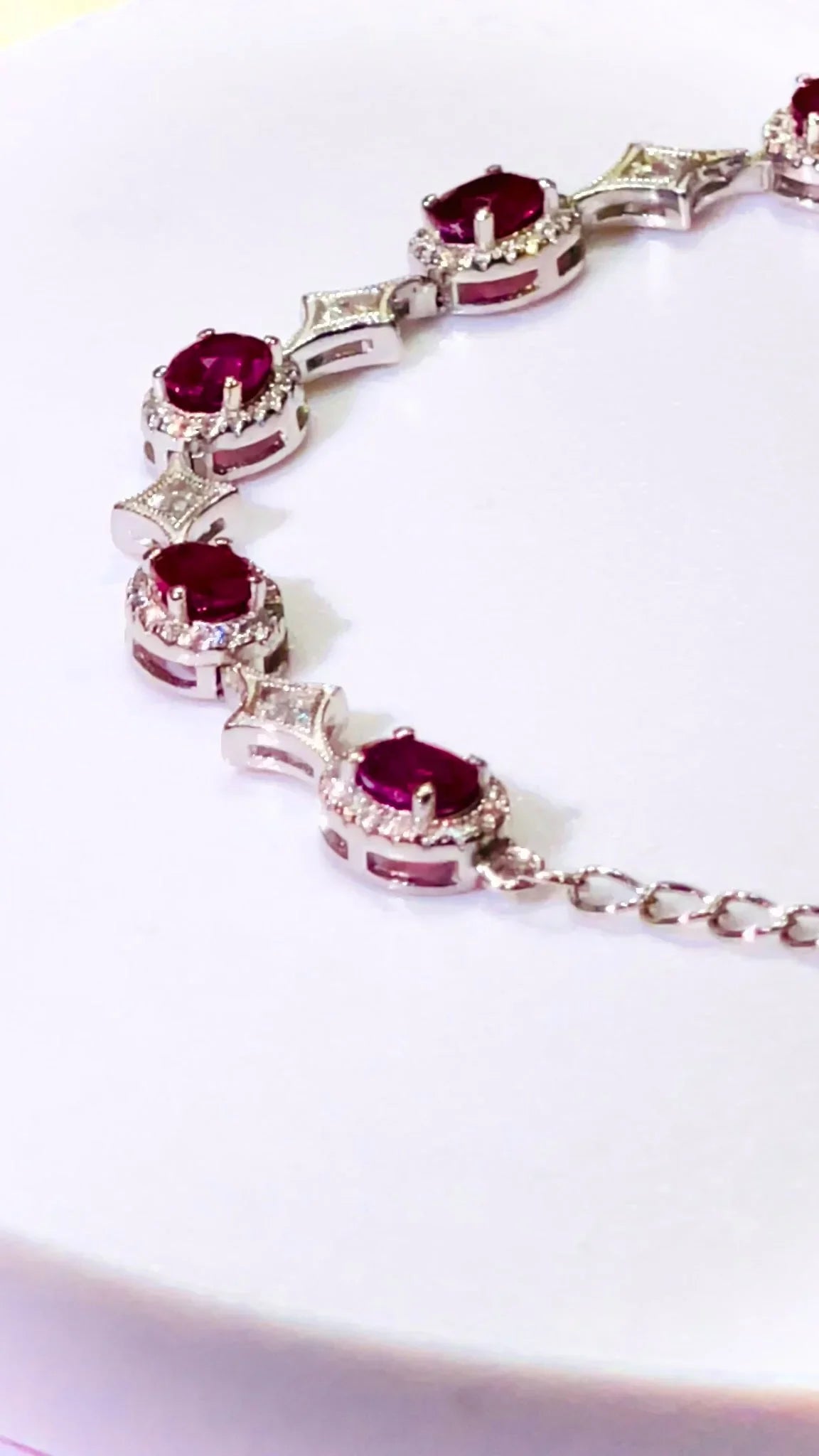 Curved view of a silver bracelet with vibrant rubies and sparkling diamonds