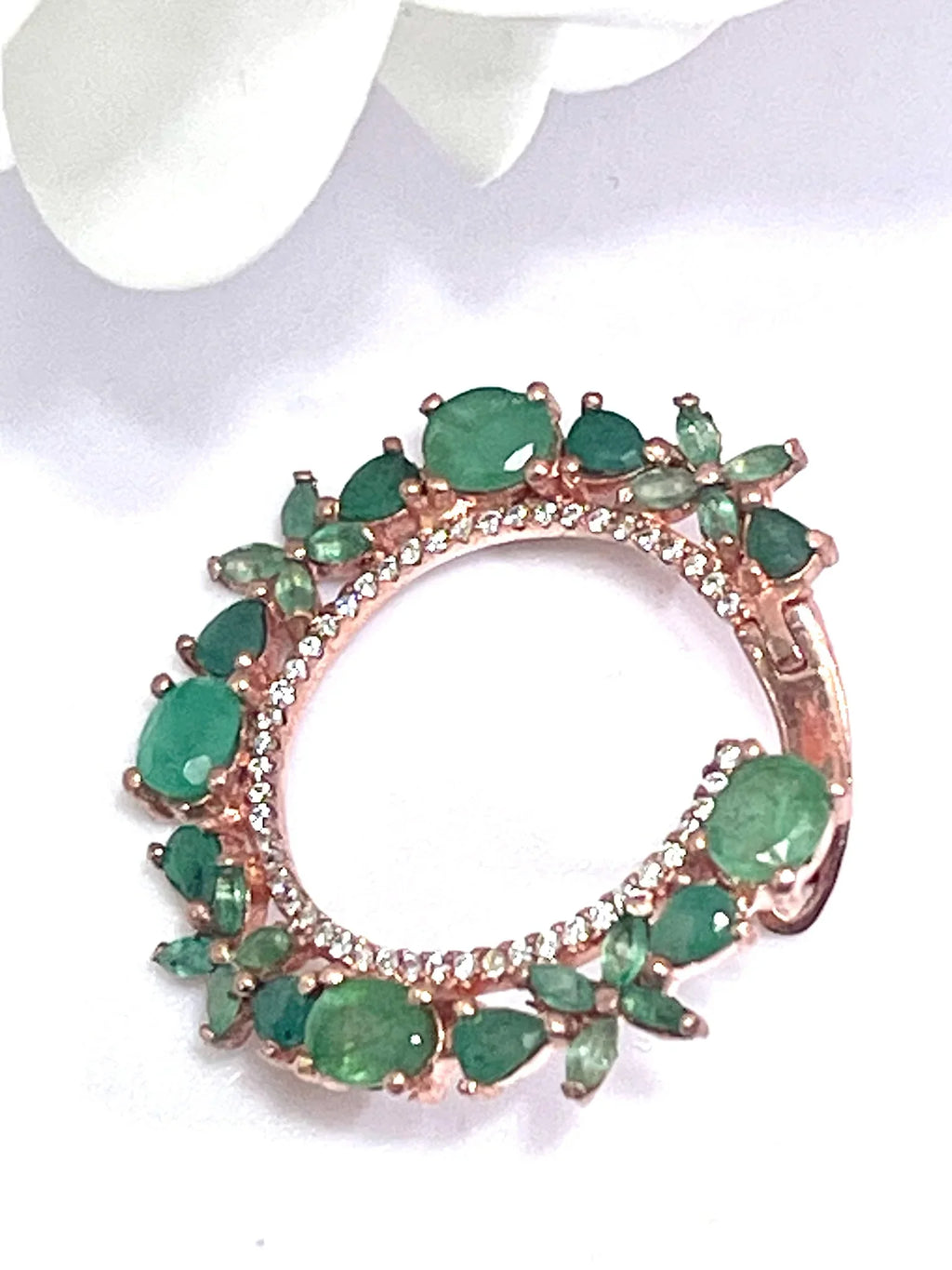 Close-up detail of one rose gold plated sterling silver hoop earring, featuring clear Colombian emeralds and subtle sparkle