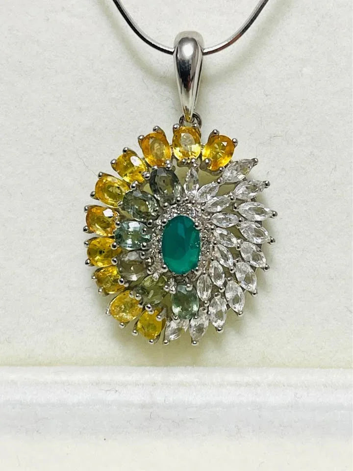 A close-up of a natural sterling silver pendant featuring agate, sapphires, and topaz in a floral design.