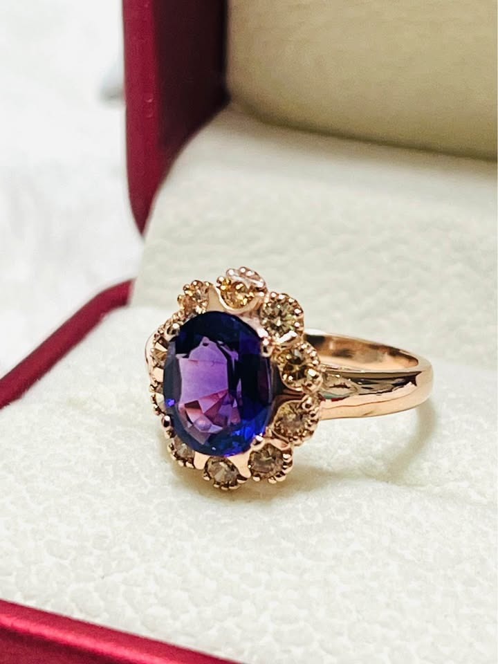 Detailed close-up of a sterling silver ring with a large oval amethyst surrounded by sparkling sapphire accents in rose gold.