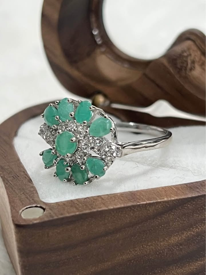  Close-up of a sterling silver ring with a cluster of natural Colombian emeralds and sparkling white stones.