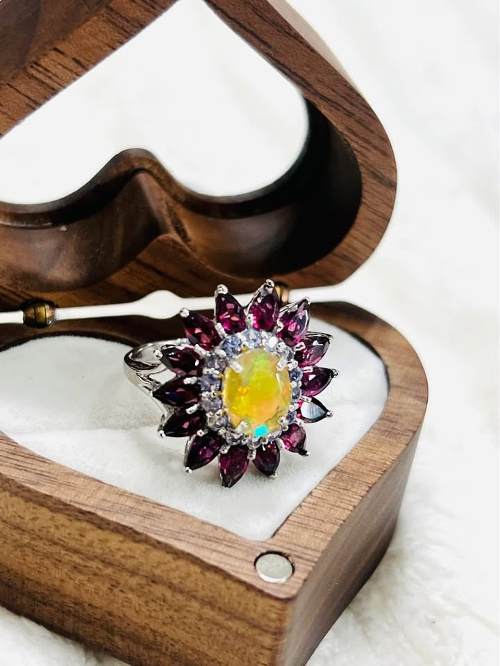 A close-up of a 925 silver ring featuring a natural fire opal and a halo of rubellite and tanzanite.