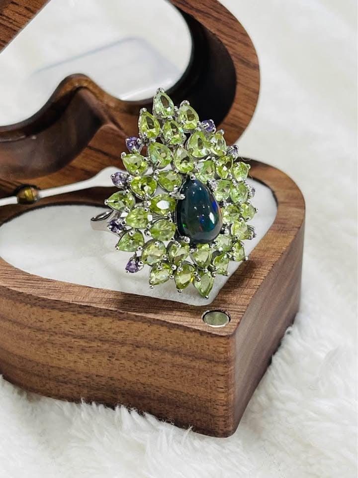  A sterling silver statement ring featuring a teardrop black fire opal, peridot, and amethyst gemstones.