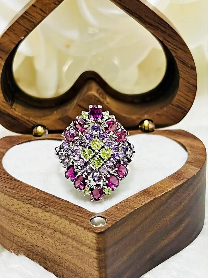 A top view of a stunning cluster ring with rhodolite, amethyst, and peridot gemstones.