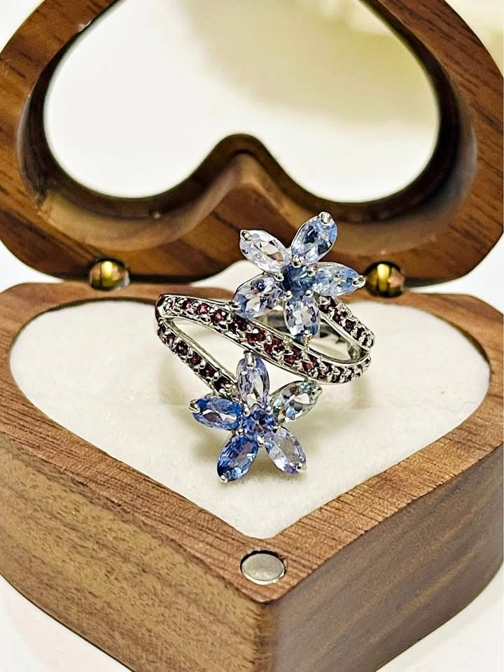 A stunning 925 silver wrap ring with two tanzanite flowers and a vibrant line of natural rhodolite gemstones.