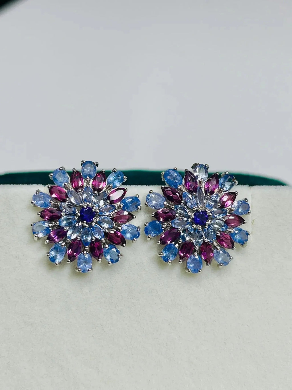 Pair of exquisite tanzanite and rhodolite sunburst earrings, featuring a vibrant cluster of purple and blue gemstones.