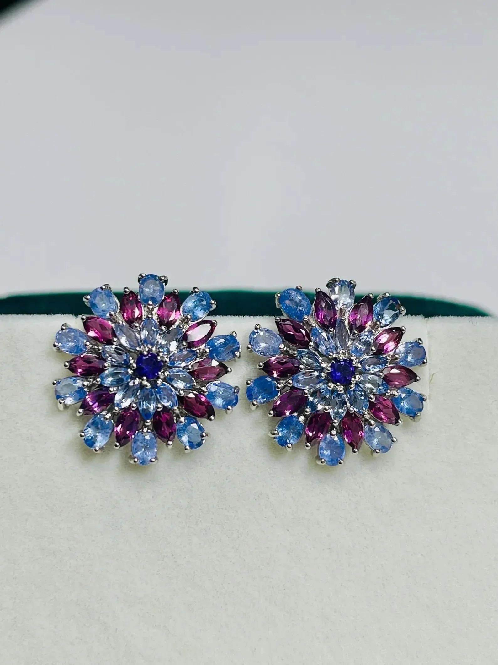 Pair of exquisite tanzanite and rhodolite sunburst earrings, featuring a vibrant cluster of purple and blue gemstones.