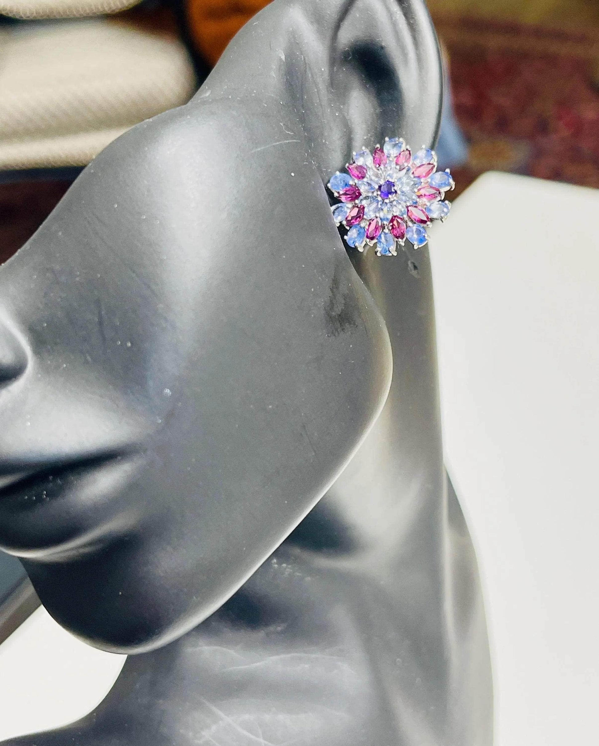 Sunburst tanzanite and rhodolite gemstone earring worn on an ear model, showing size and vibrant color on display.