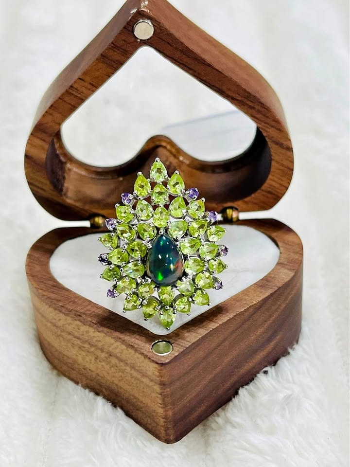 A unique sterling silver ring featuring a black fire opal centerpiece with a halo of green peridot.