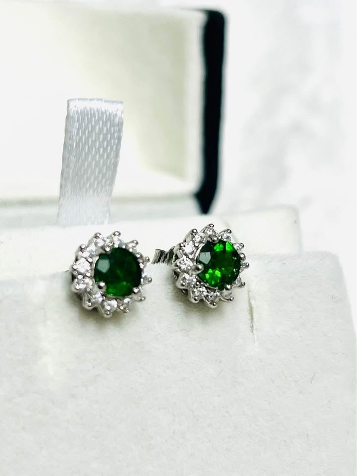 Vibrant natural chrome diopside stud earrings in a white gold setting, angled view.
