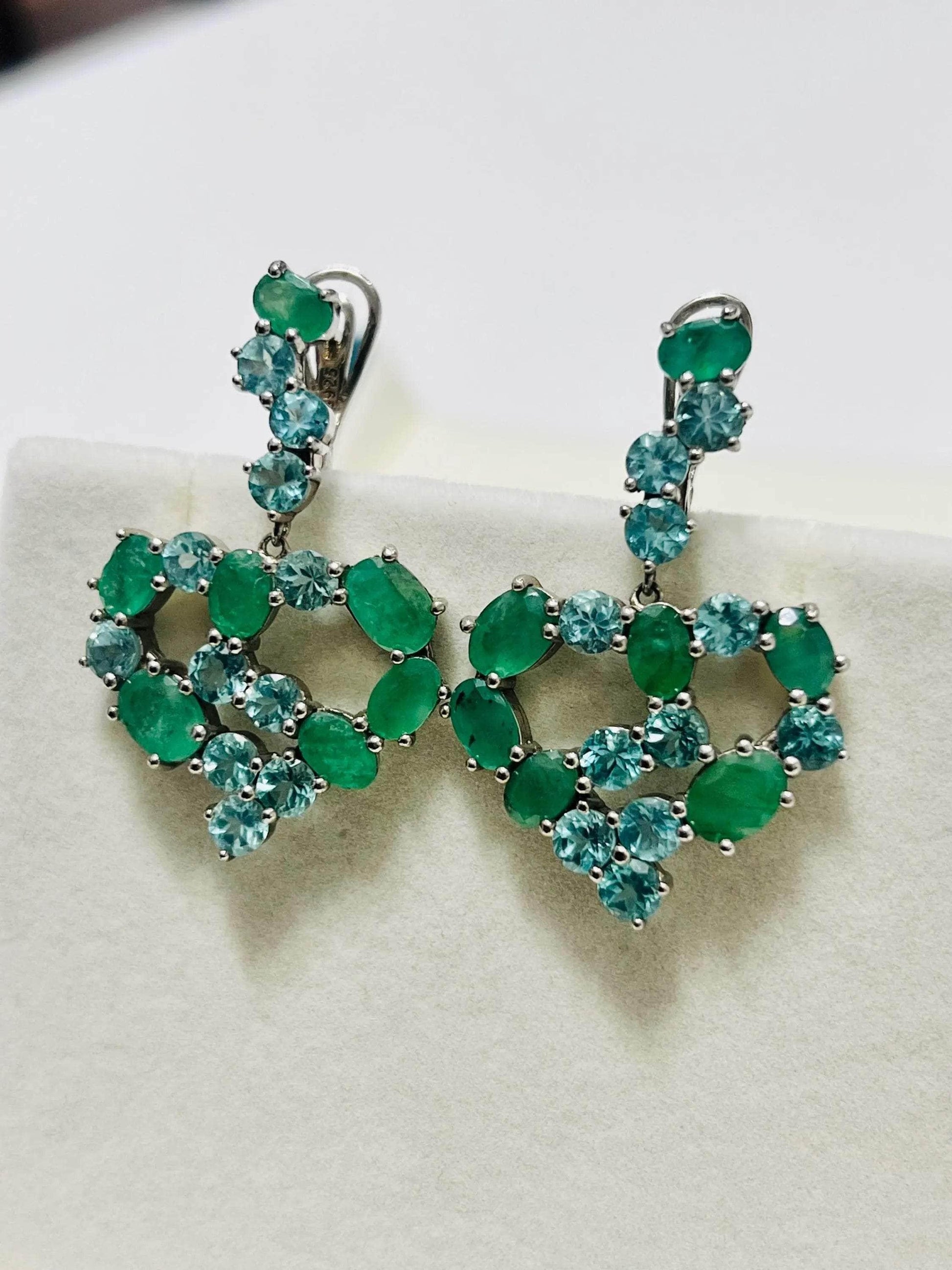 Angled view of striking vintage emerald and blue apatite heart earrings, showcasing their vibrant gemstones.
