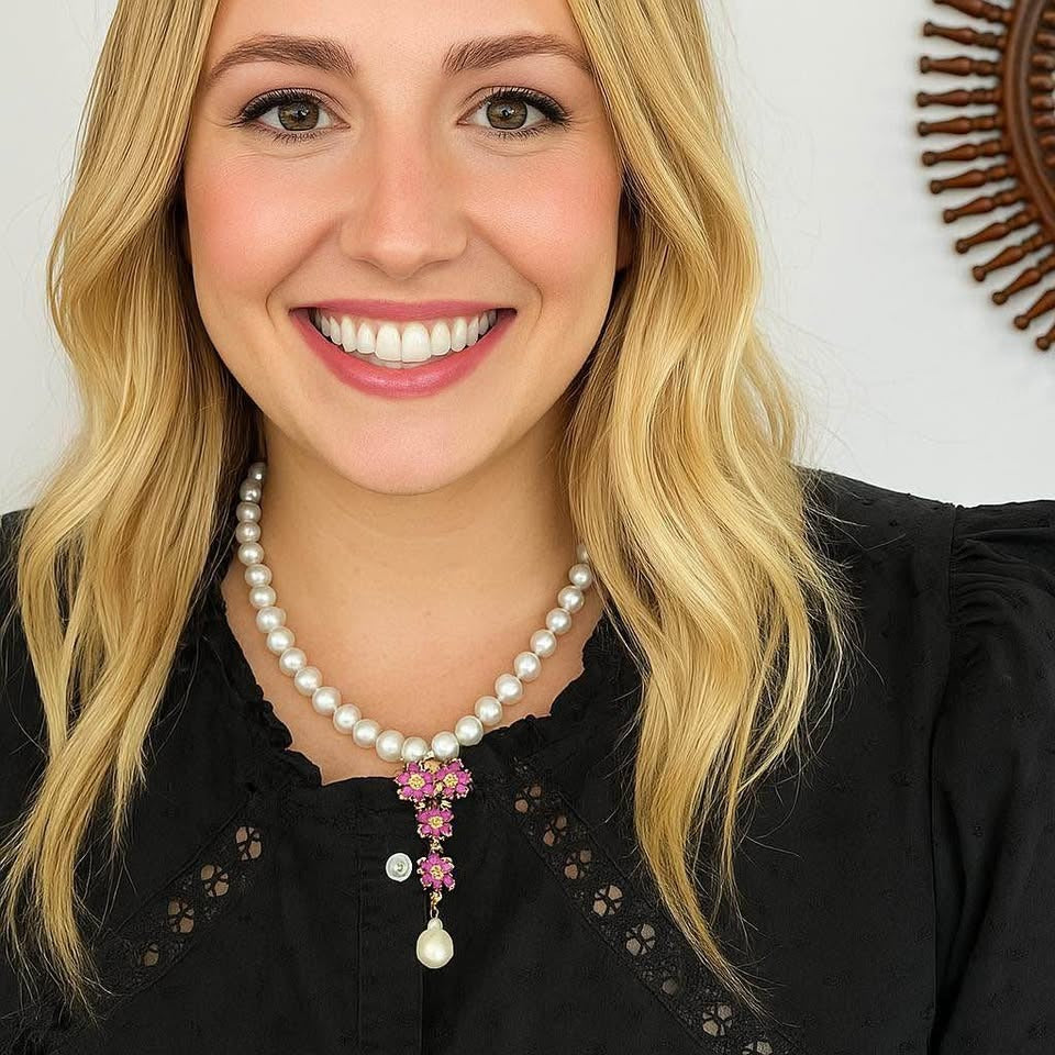 Smiling woman wearing a natural freshwater pearl necklace with a pink ruby floral drop pendant.