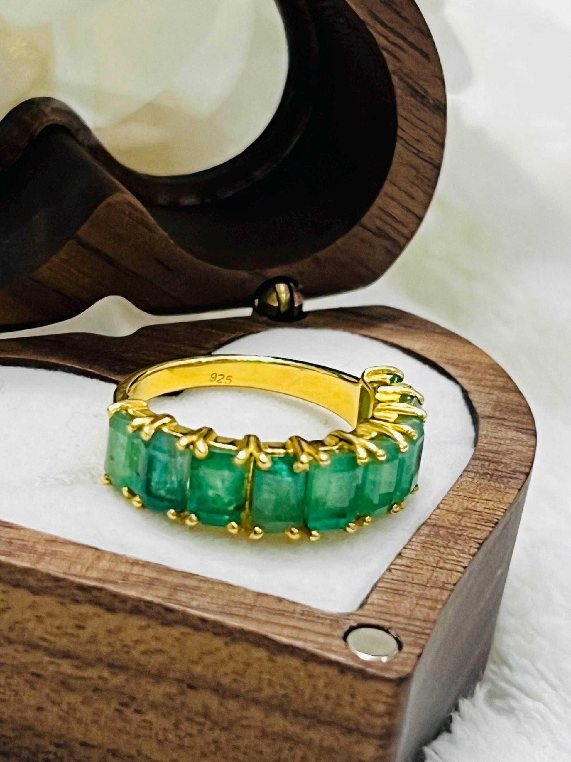 Front view of a beautiful Zambian emerald flower ring with vibrant green gems, showcased on a black velvet display.