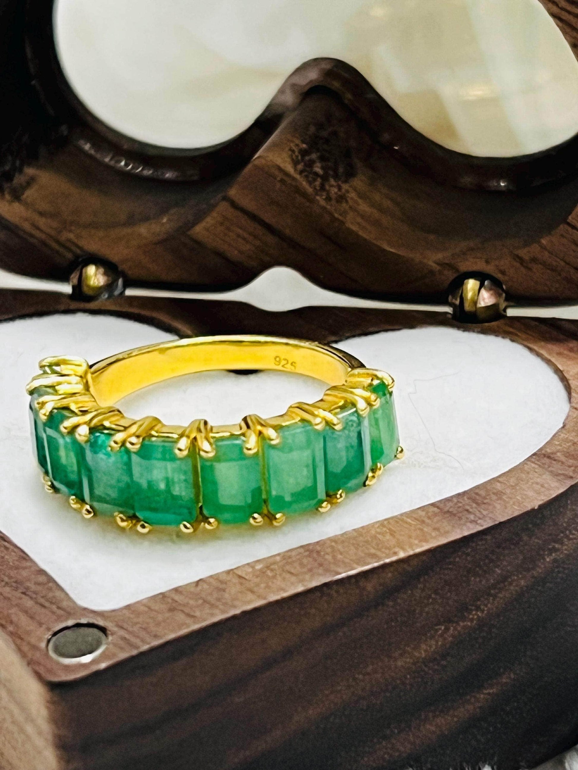 Close-up of a stunning Zambian emerald flower ring with sparkling accents, displayed on a black velvet stand.